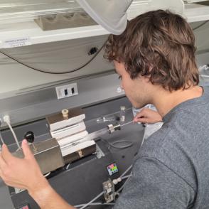Nick Beres sliding a substrate into a tube laying on the furnace to prepare for CVD.