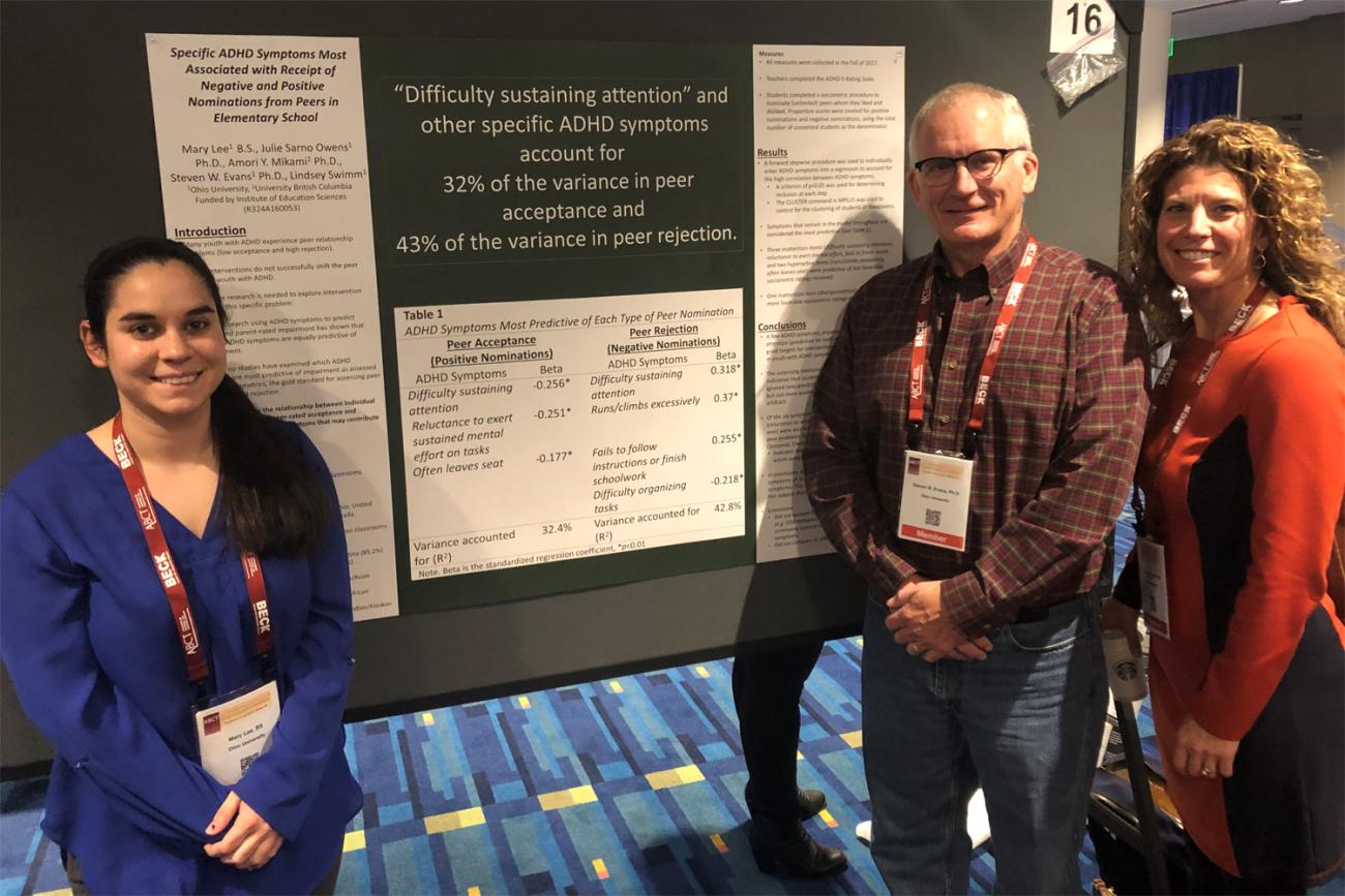 Student researcher with Steve Evans and Julie Owens in front of her research poster