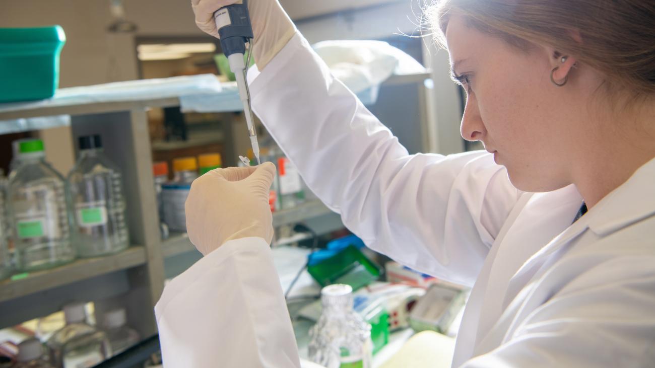 Woman in a chemistry lab dropping liquid into sample container