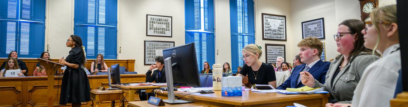 Students participate in a mock trial in a court room.