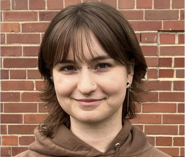 A headshot of Mary Kancler, wearing a brown hoodie