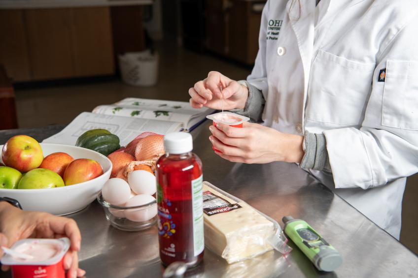 Closeup of a student's hands working with food ingredients in a kitchen