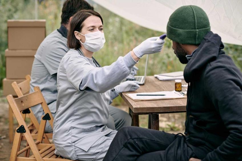 Public health worker takes a community member's temperature at a mobile clinic