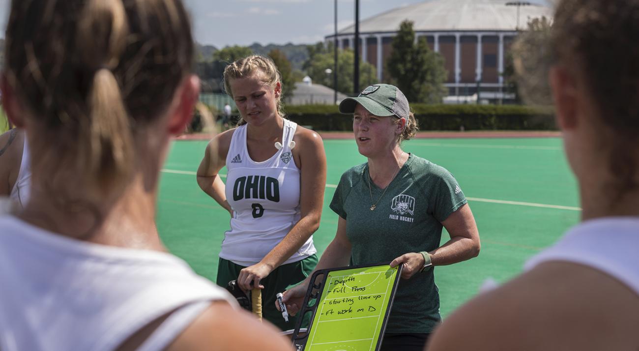Ali Johnstone with clipboard coaching OHIO field hockey team 