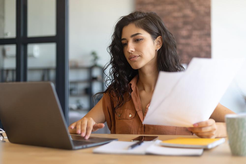 Woman at a desk with papers and a laptop.