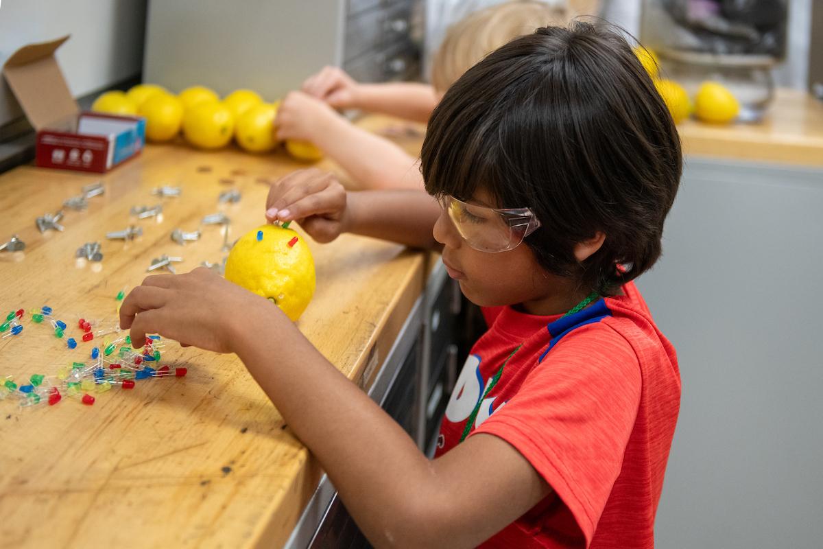 A young boy doing experiments on a lemon.