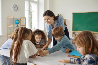 Teacher helping a group of students sitting together at a table.