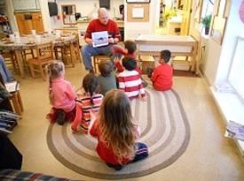 Pre-K Classroom with teacher reading to students sitting in a circle.