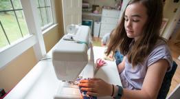 Student sewing on a sewing machine.