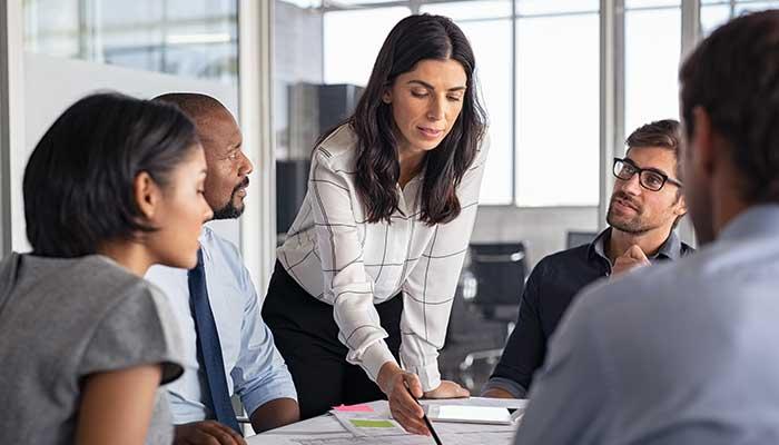Lead engineering manager standing at table with engineers discussing technical writing