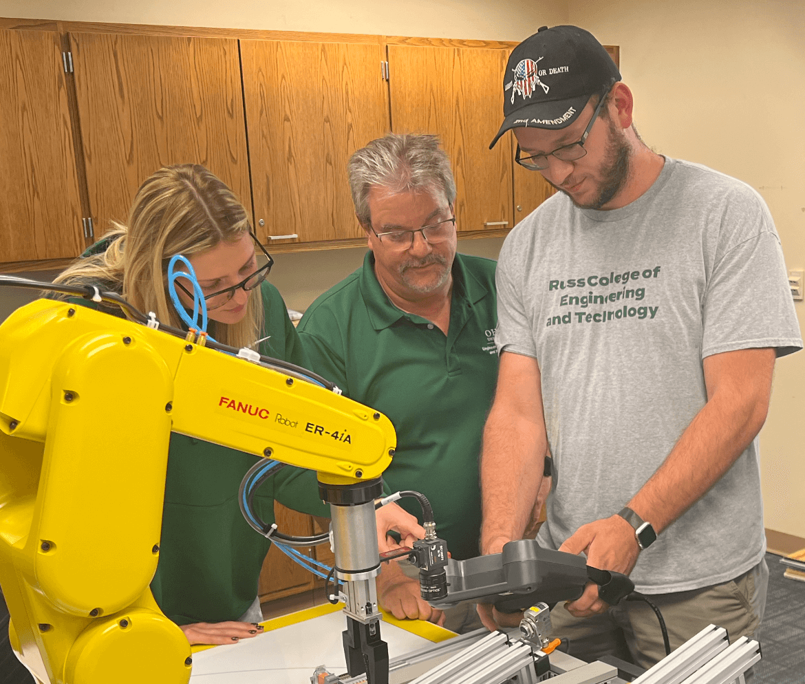 Teacher overseeing two students using some kind of robotic arm