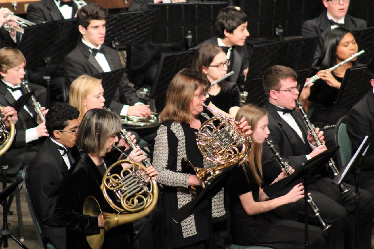 People in an orchestra playing French Horns