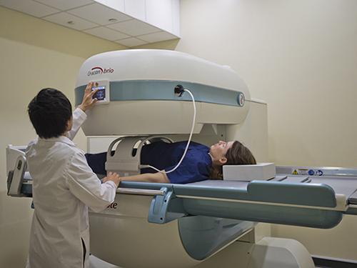 A patient goes through an MRI machine with a medical professional standing next to them