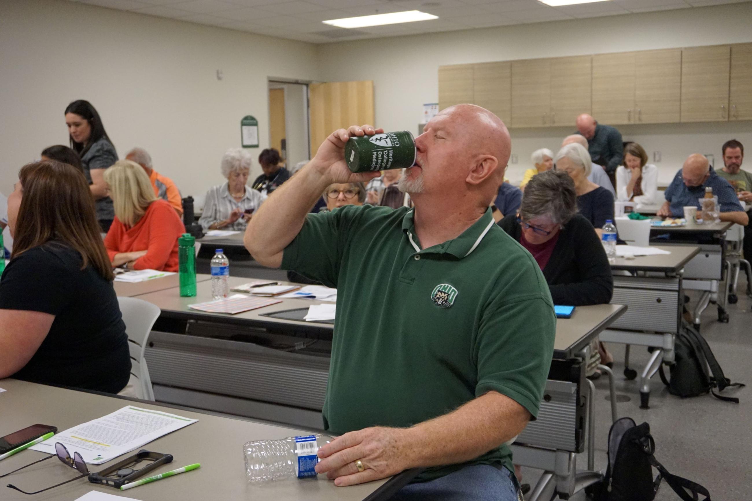 A standardized patient pretends to drink out of a mug