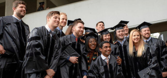 Graduating students grouped together for a photo wearing their academic regalia