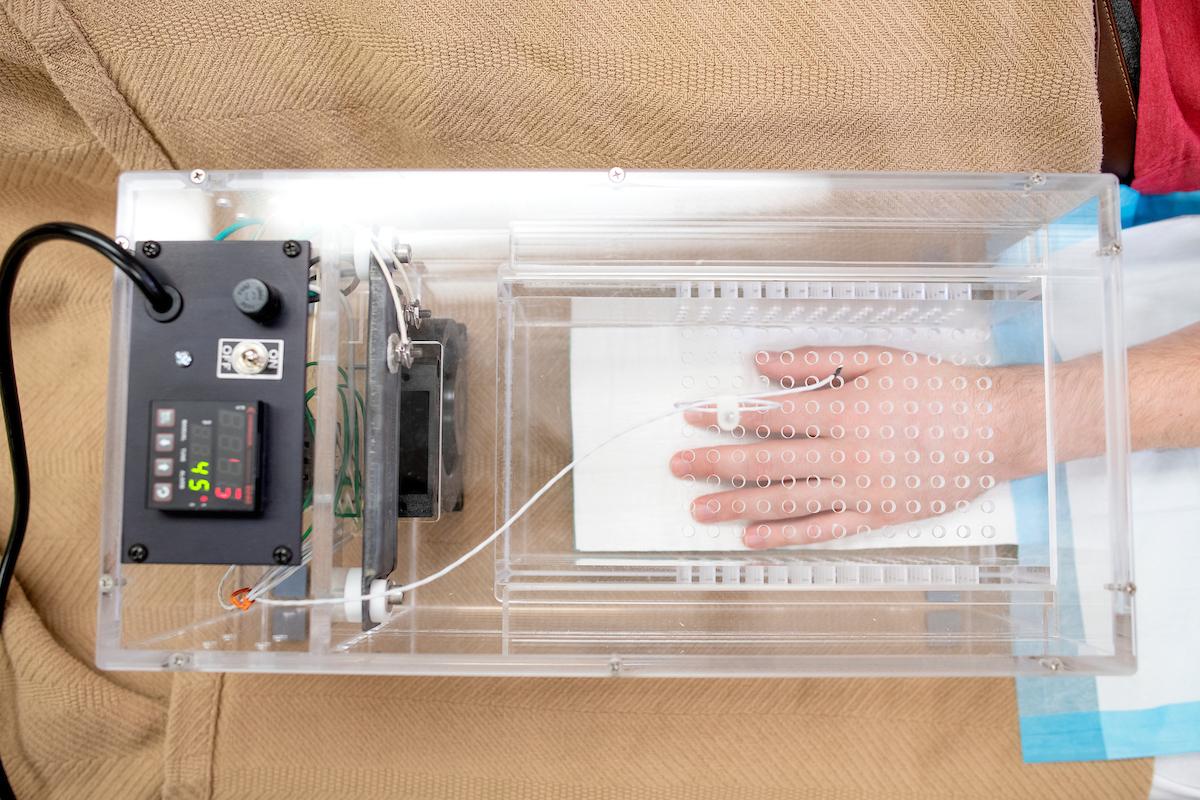 A participant places their hand in a piece of medical equipment.