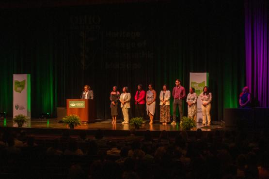 Students on stage waiting to receive award during HCOM award ceremony