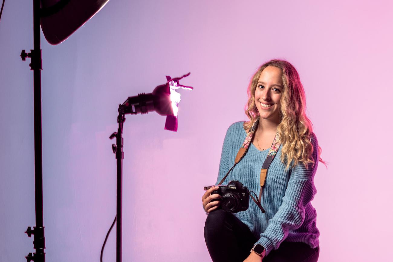 woman sitting in a photography studio with a camera and lights set up nearby