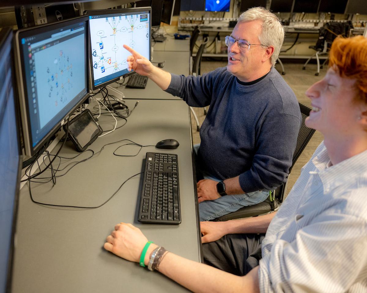 Prof. Bruce Tong works with a student analyzing a network diagram.