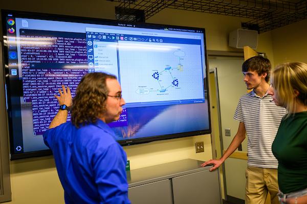 Students and faculty working on a large screen in the ITS labs