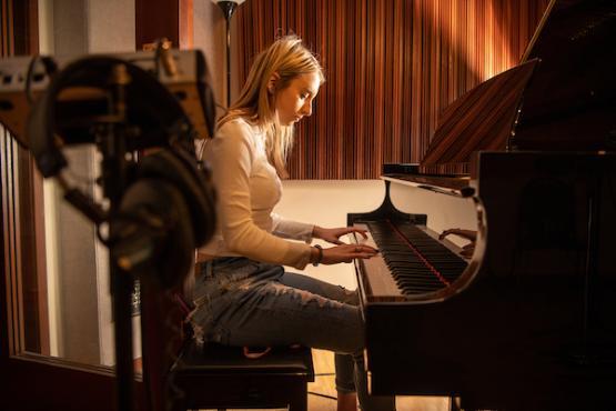 woman playing the piano in a recording studio