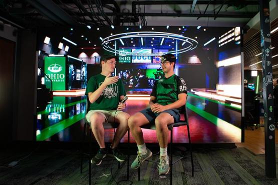 Two Esports Newscasters sit in front of an LED wall.