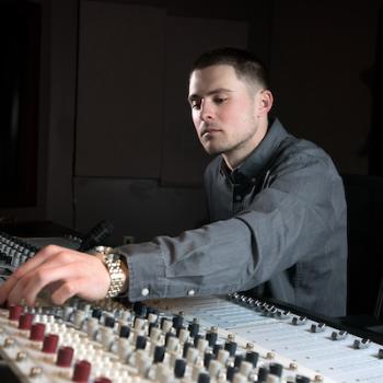 A student balances knobs on a sound mixing board