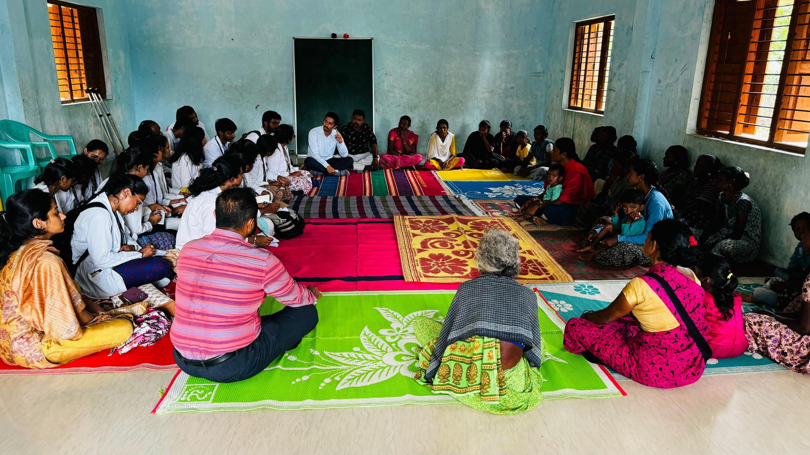 large group of people sitting in a circle facing one another