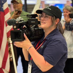 Woman in baseball cap holding video camera