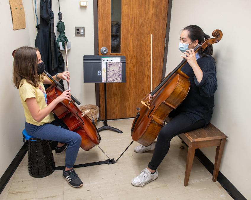 Woman teaches a young girl to play the cello