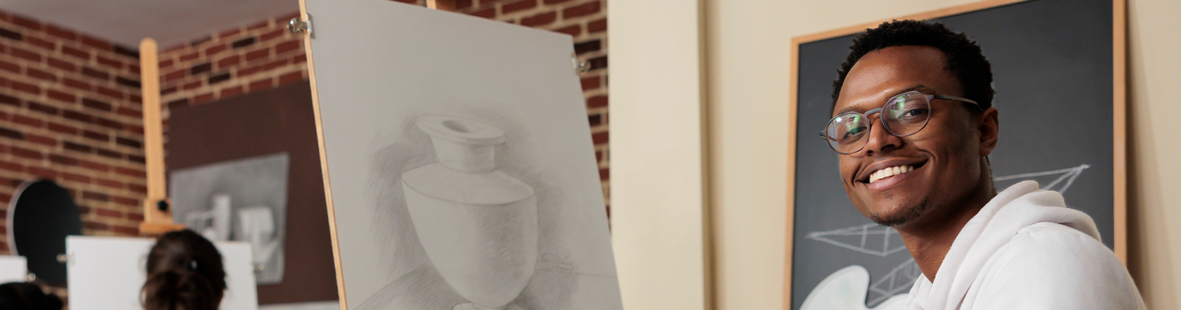 A man sits in front of a drawing on an easel