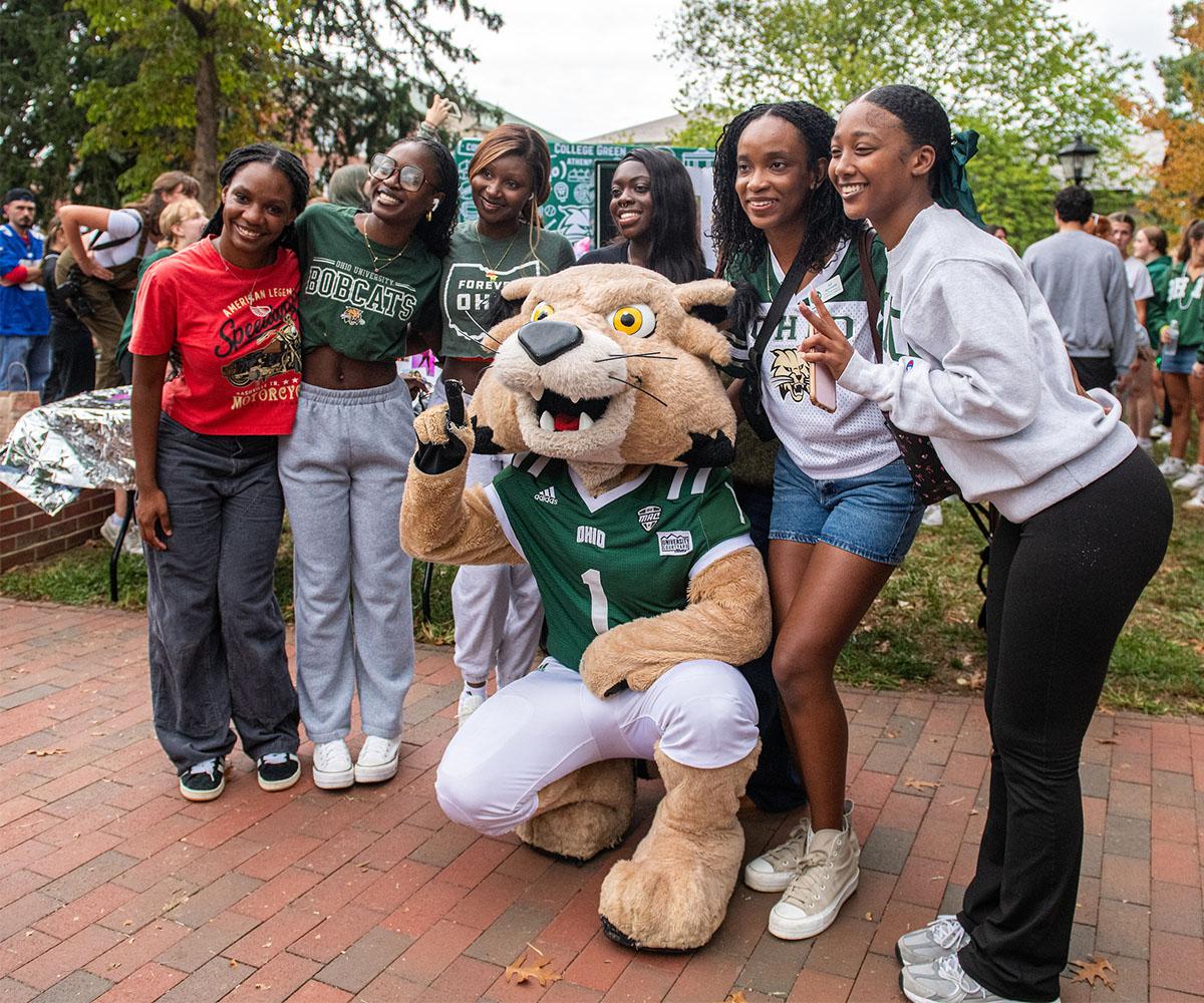 Students pose with the Ohio University mascot, Rufus the Bobcat, for a photo at a pep rally.