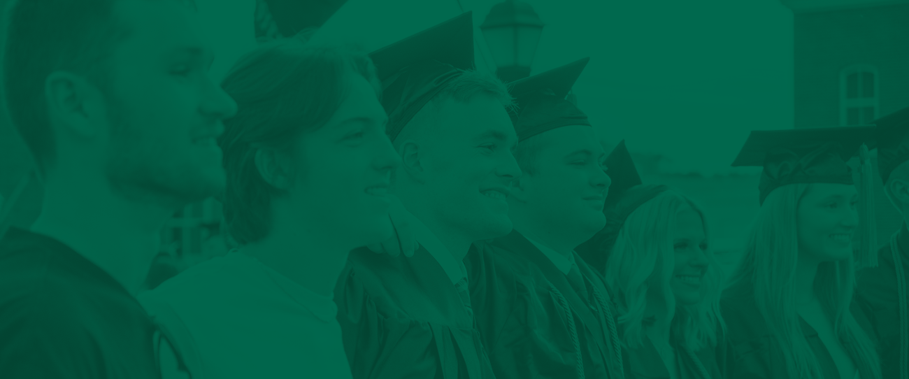 group of male and female students in caps and gowns smiling and looking ahead