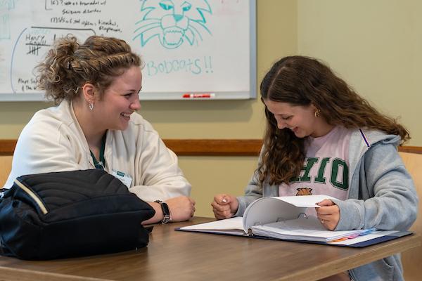Two female students smiling at table
