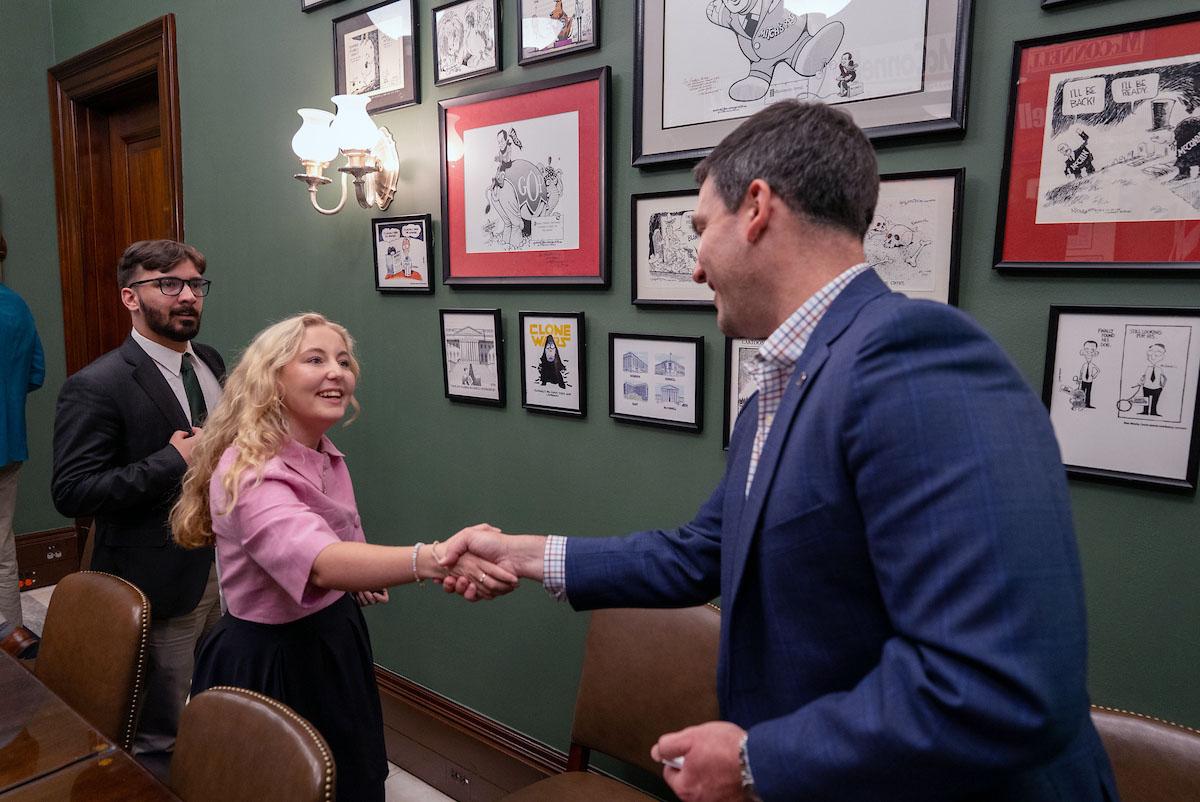 A young woman shakes hands with a middle aged man