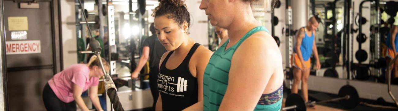 Student employee training a member in the WellWorks fitness center.