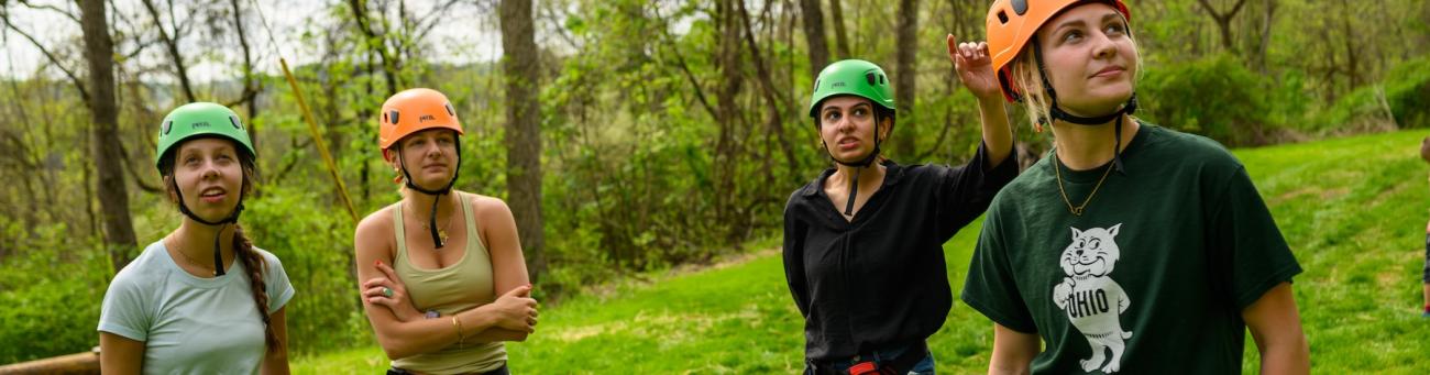 students standing next to the challenge course in helmets