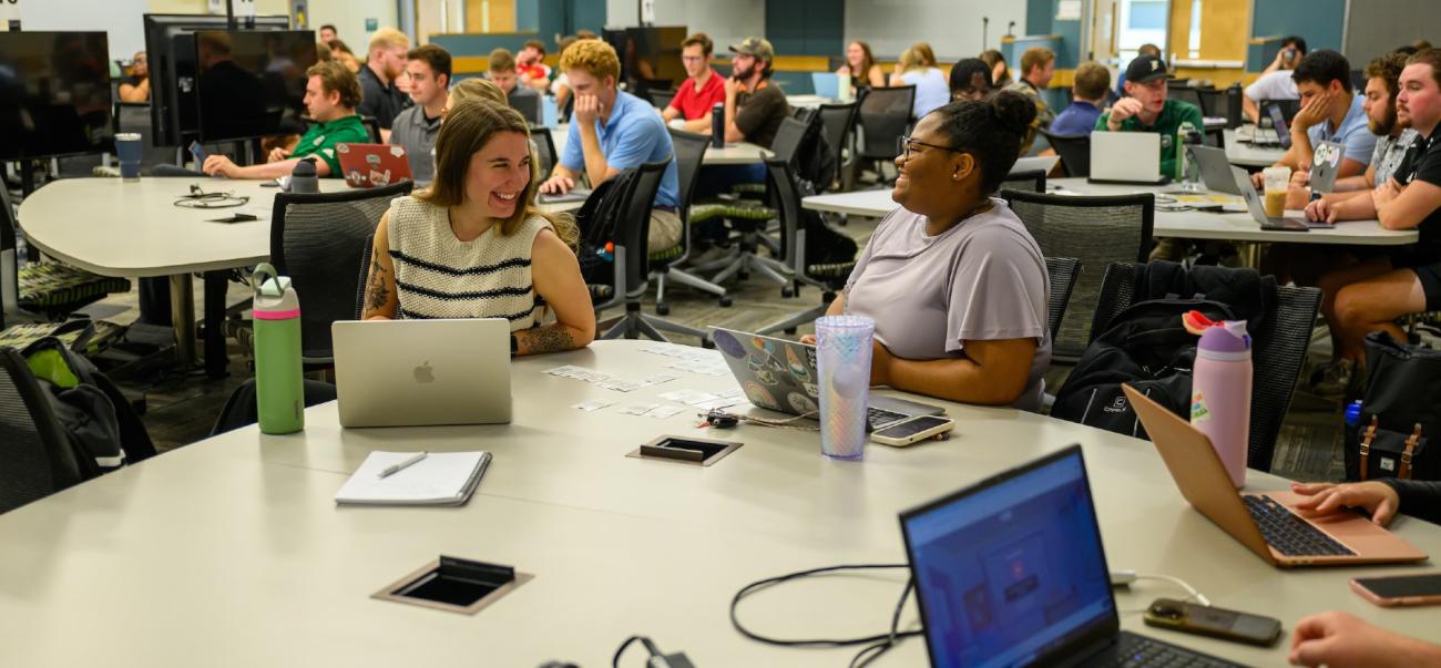Students participating in Business Venturing Class at round tables with open laptops