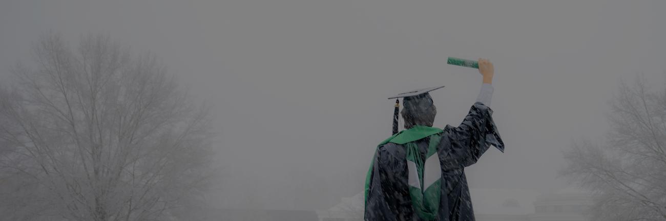A 2024 OHIO graduate holds up diploma in a December snowstorm