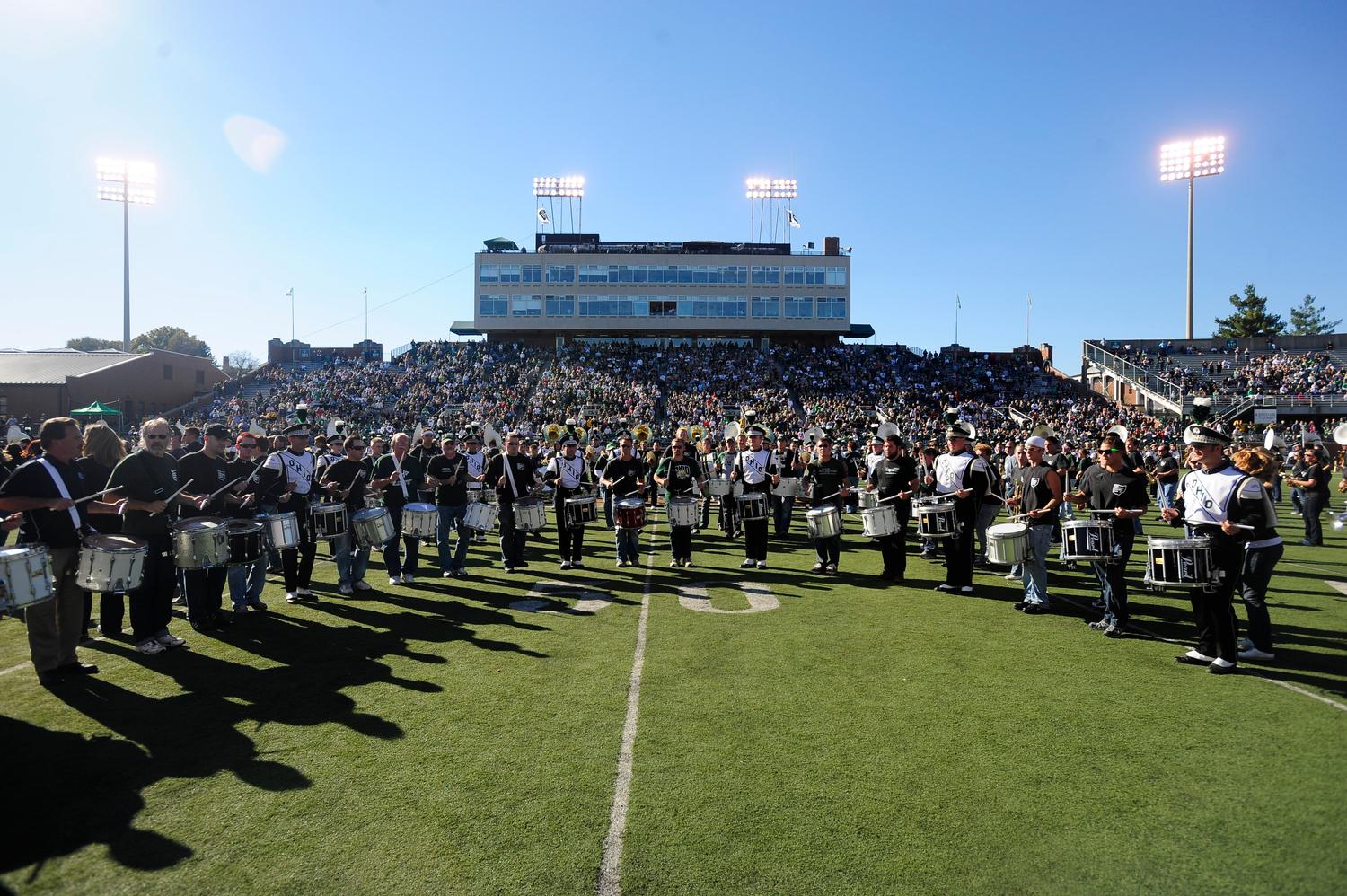 Marching 110 alumni play their instruments on the field