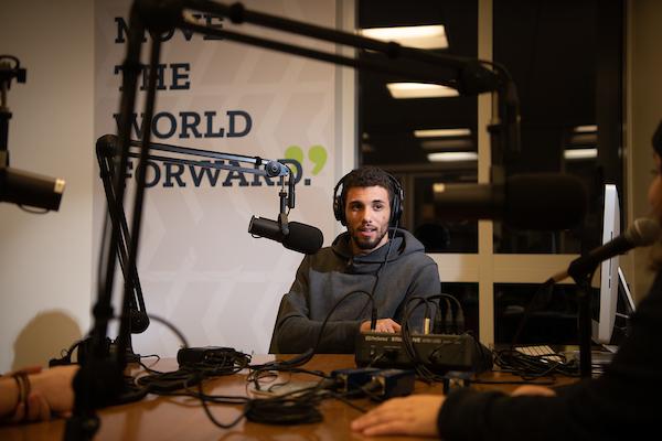 man sits at microphone in podcast studio at night