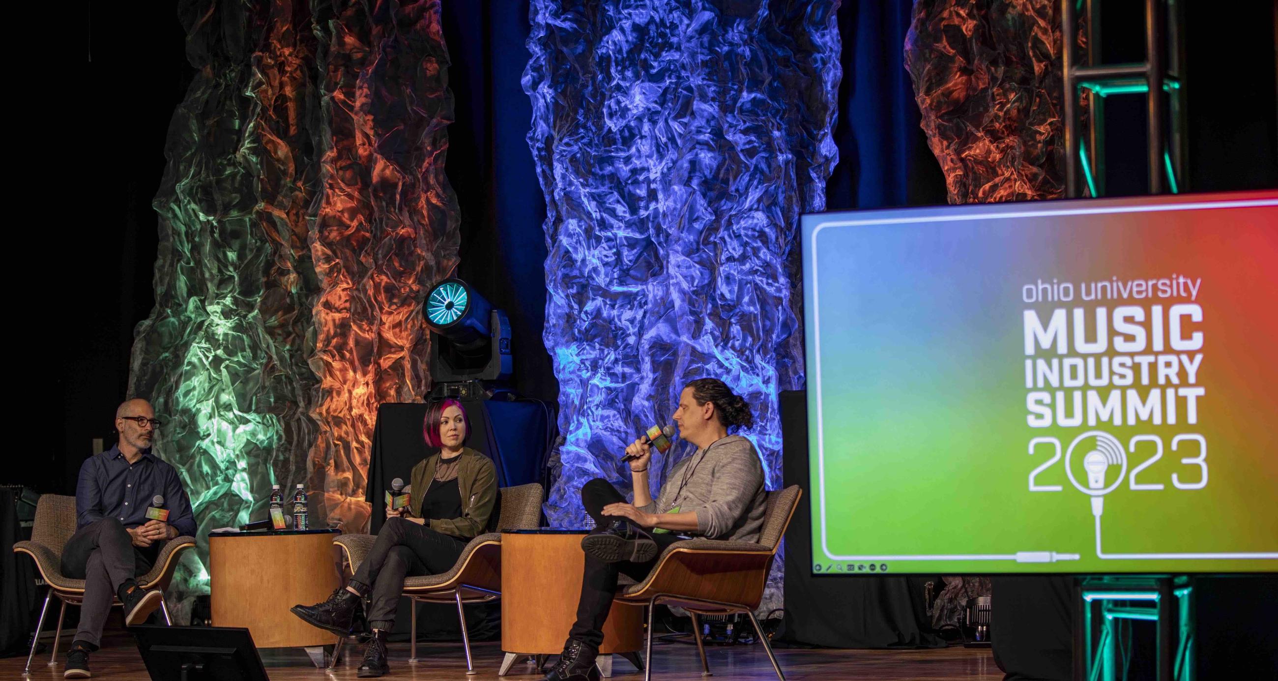 Three panelists talking on stage