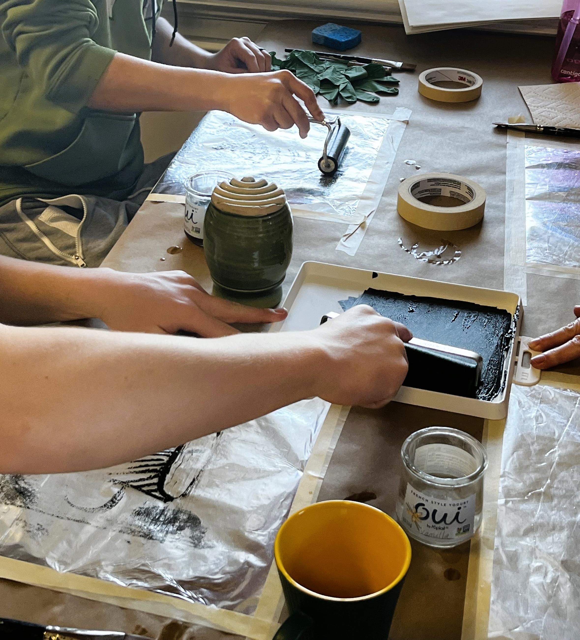 People sitting at table applying ink with rollers