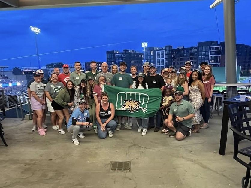 Group photo of alumni at baseball game.