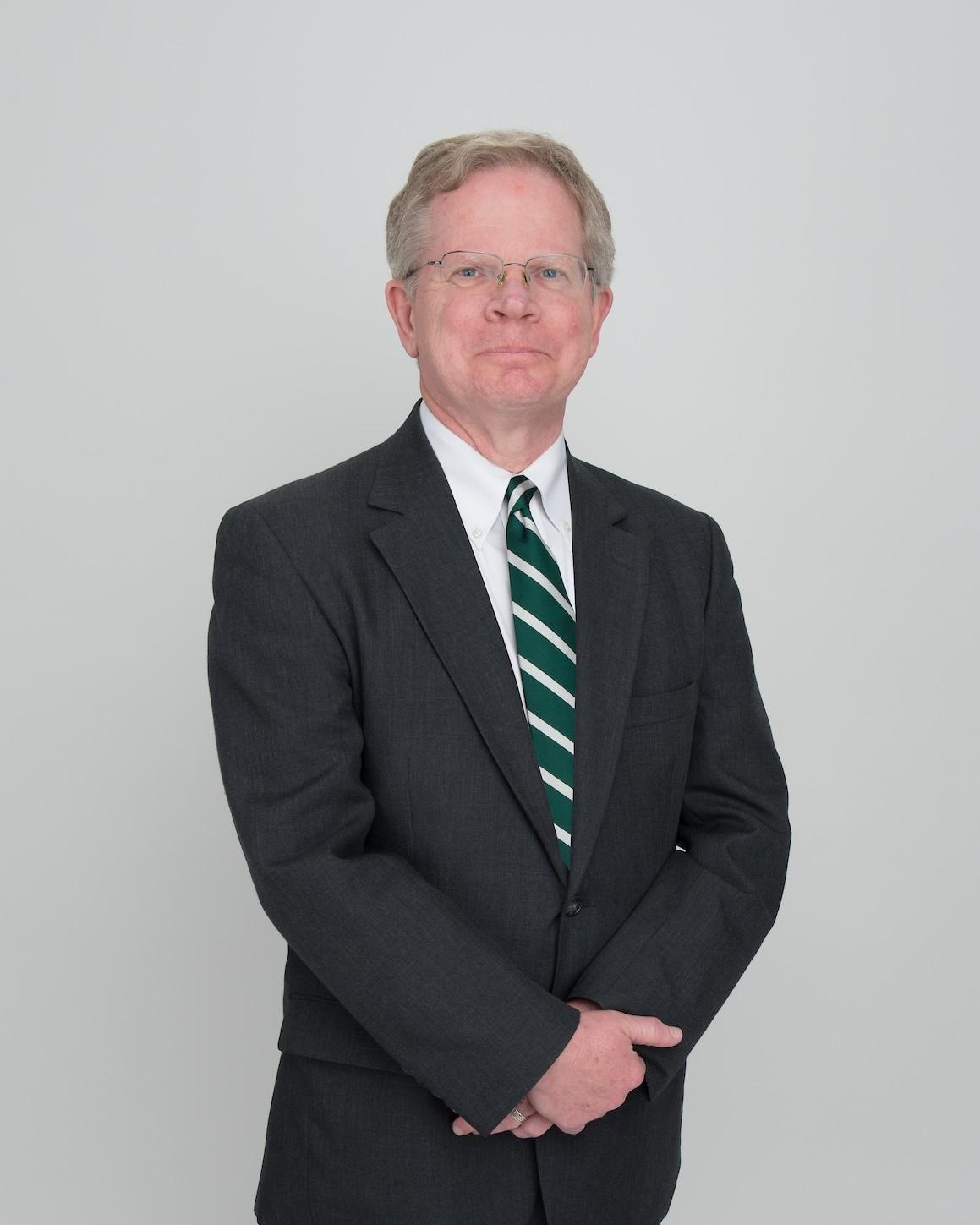 Dr. Richard W. Greenlee, wearing a grey suit and striped tie