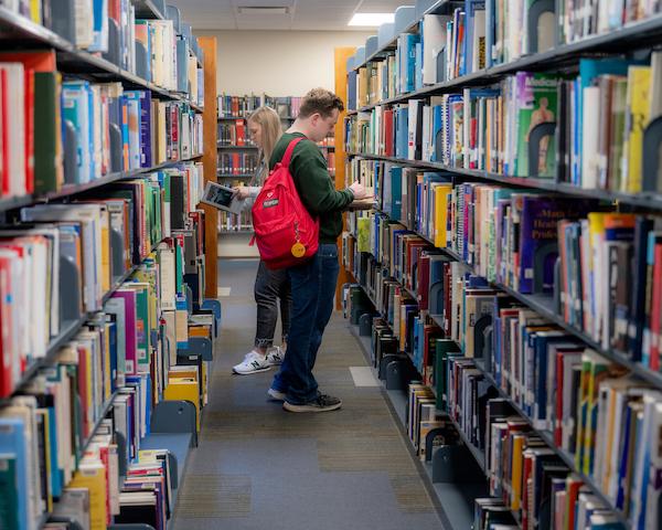 Student reading books in the Hannah V. McCauley Library stacks
