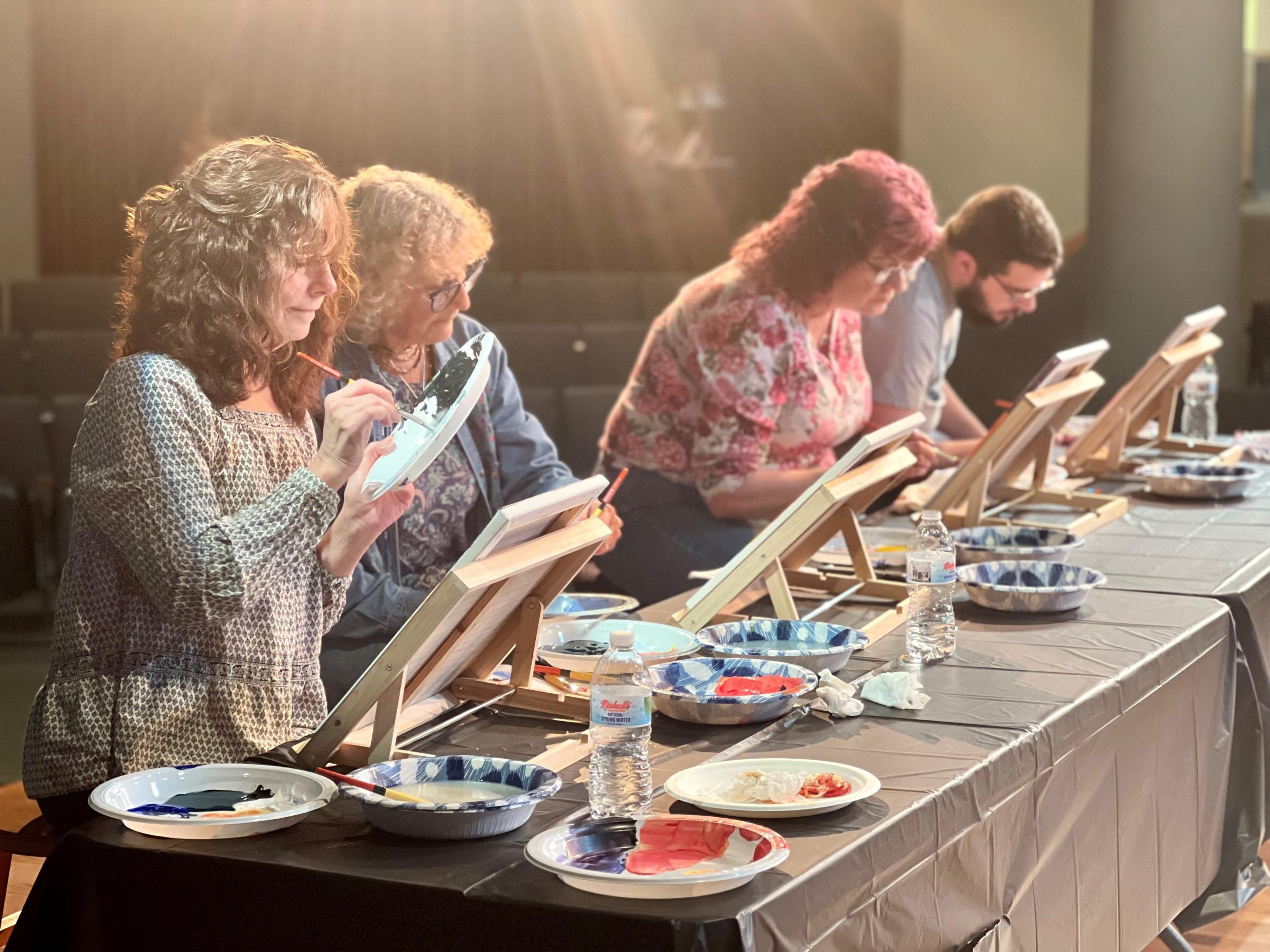 3 woman and 1 male painting in an art class
