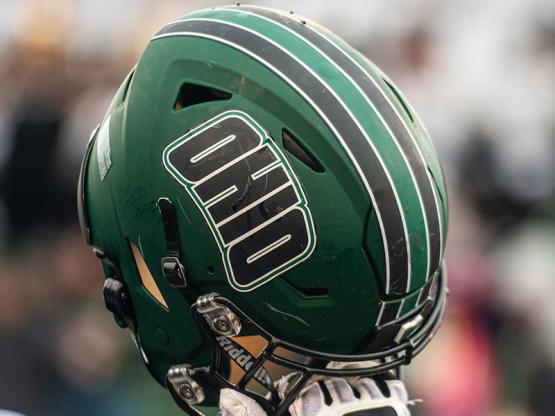 Gloved hand holding OHIO football helmet into the air.