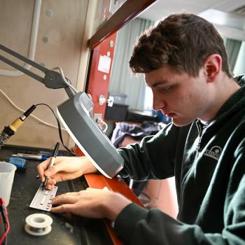 Student works on electrical circuits under a magnifying glass
