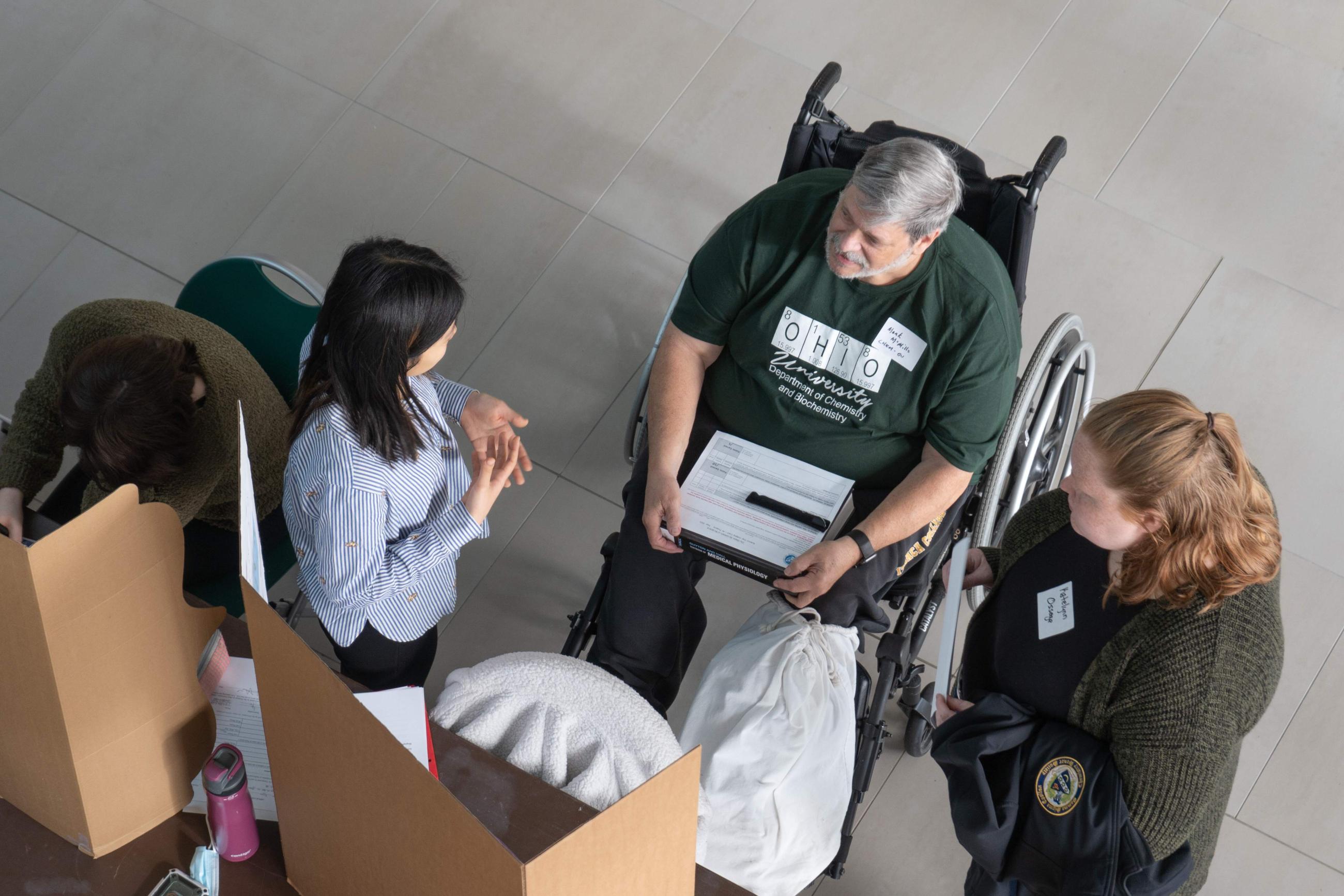 Group of students and instructor in wheelchair viewing science display